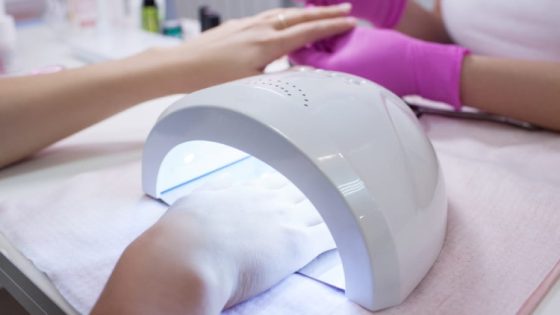 UV lamp gel polish manicure process. Salon procedure. The master coats the client's nails with a varnish.